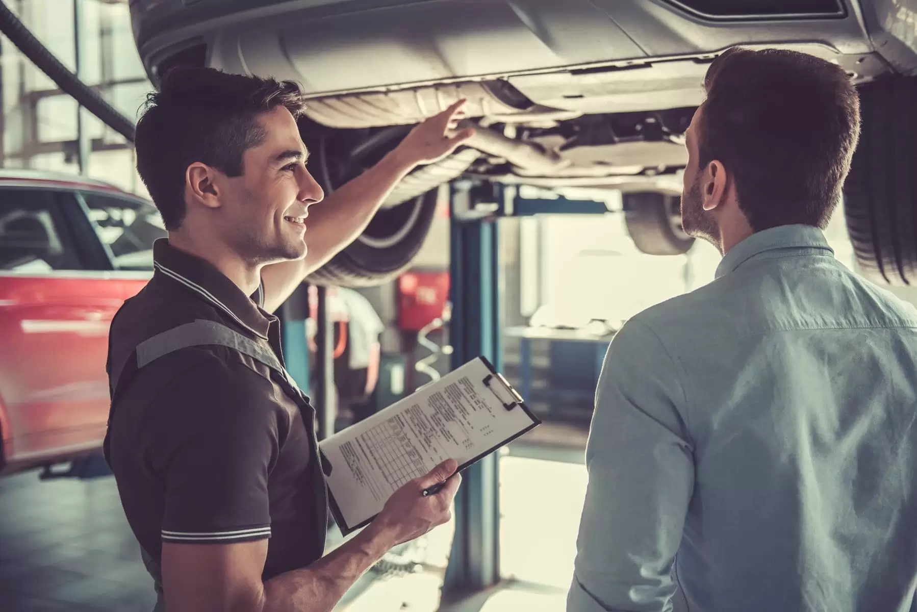 Man talking with mechanic at car garage
