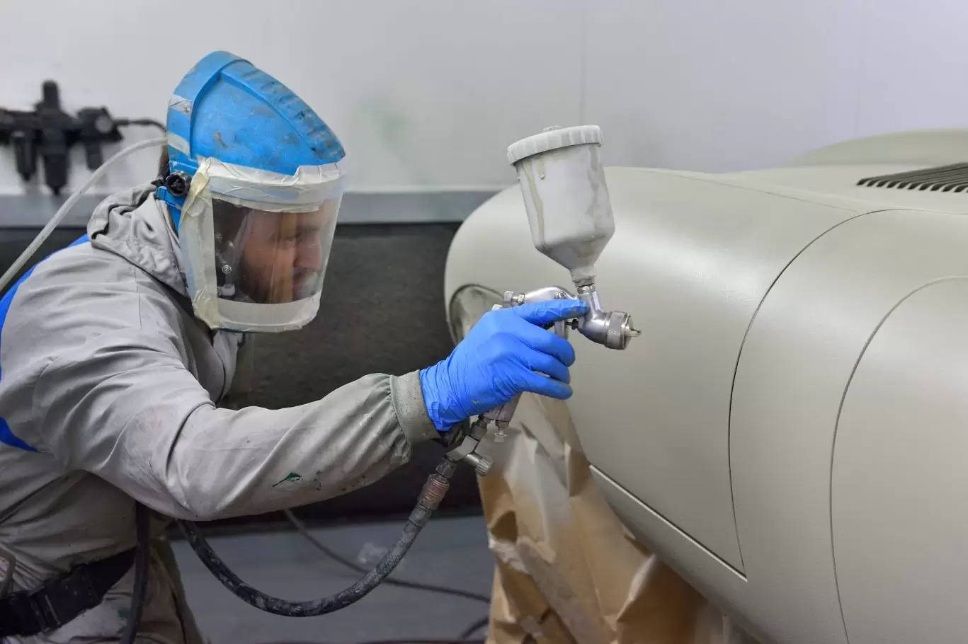 Man in workshop spray painting vehicle